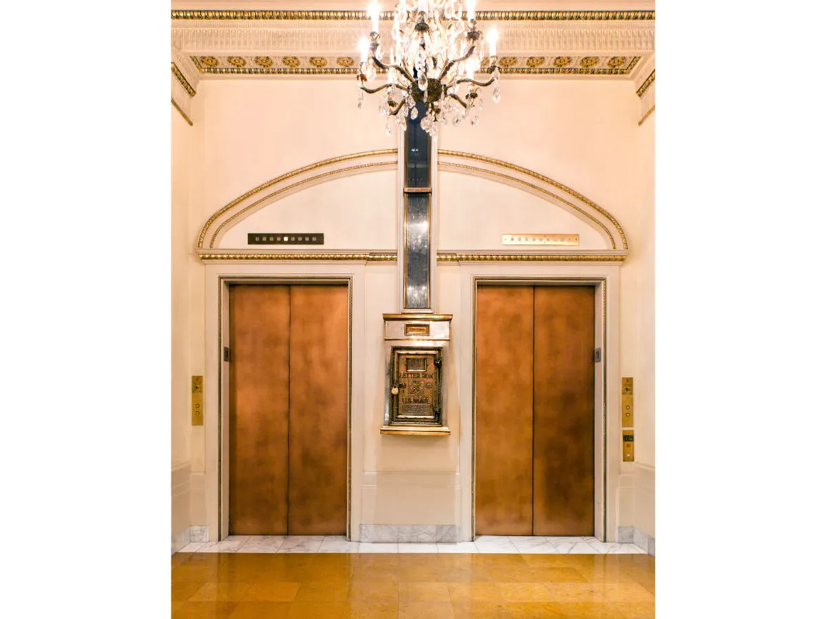 This image features the hotel's elegant elevator lobby, with ornate chandeliers, decorative wall elements, and a control panel. The mood is sophisticated and welcoming, capturing the moment of arrival and anticipation of exploration.