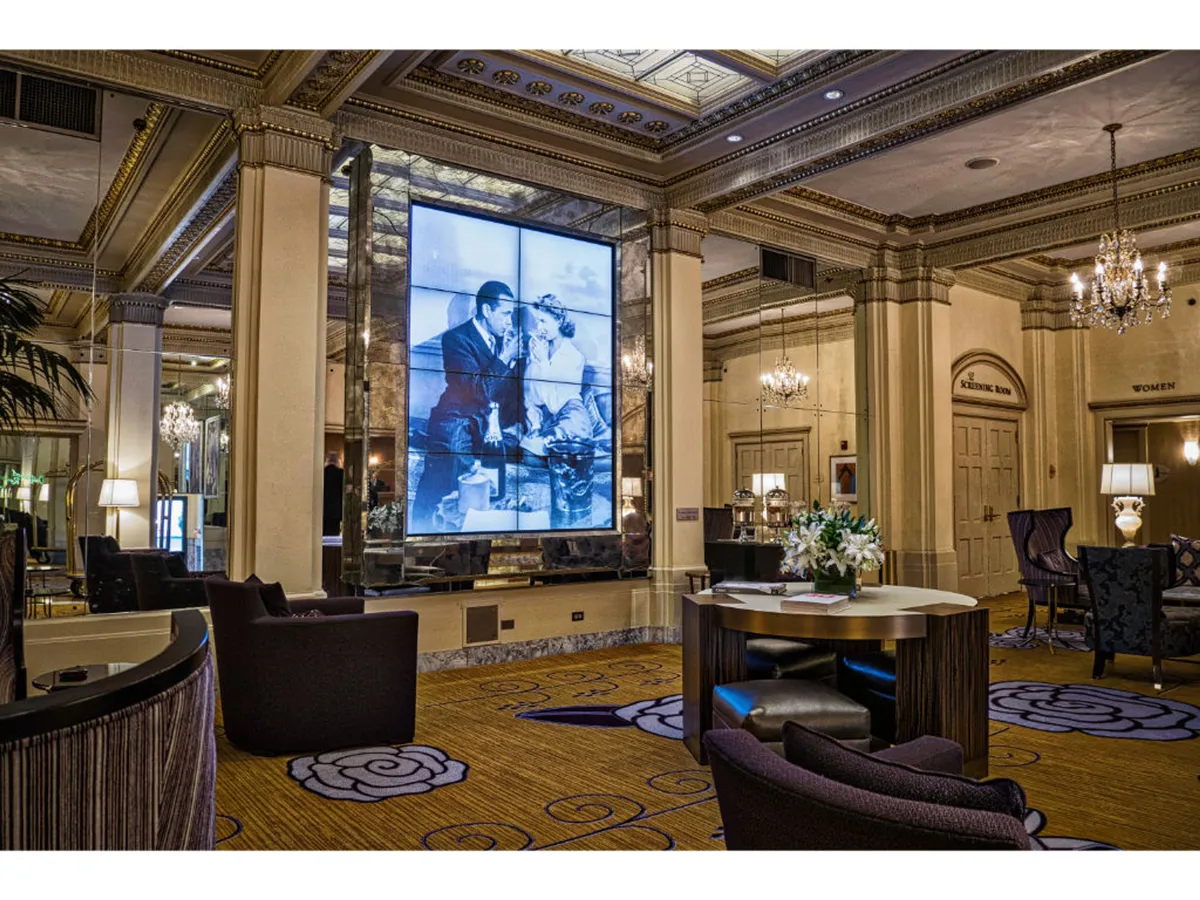 A tastefully arranged interior showcasing modern digital artwork, sparkling chandeliers, and a comfortable furniture layout. The scene is set for both quiet gatherings over drinks and elegant business meetings, highlighting the hotel's versatility.